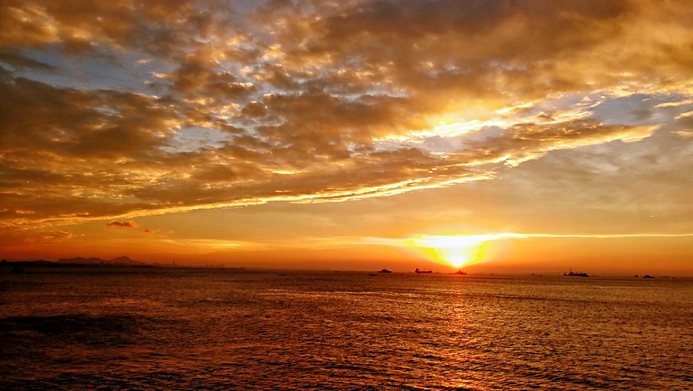 夕阳西下彩绘泼墨的海边 海水中上演如水幕电影的迷幻 坐在火烧云